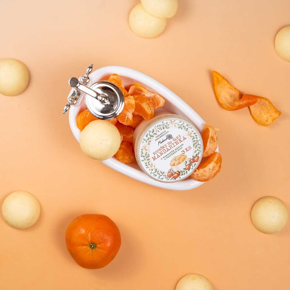 Medarek Mandarin Bath Melts in a miniature bathtub with tangerine segments and peels on an orange backdrop.